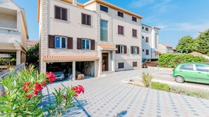 A two-story residential building with a tiled driveway and a garage. - Apartment Karlo (Kastela)