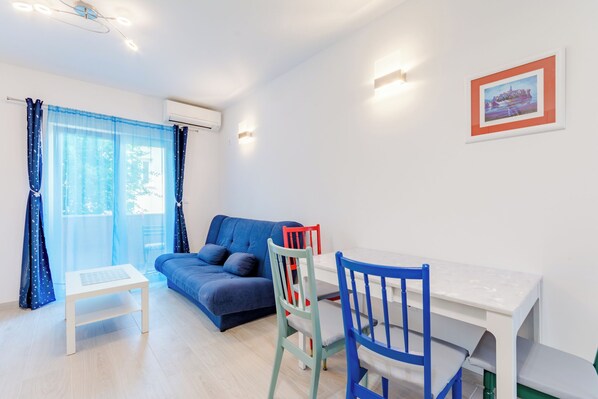 Un salón moderno con un sofá azul, una mesa blanca y una silla roja y azul.