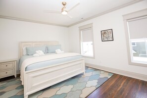 A bedroom with a bed, a nightstand, a ceiling fan, a window, and a door.