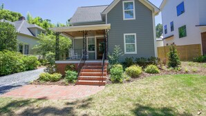 A two-story house with a front porch, a brick pathway leading to the entrance, and a well-maintained garden with various plants and shrubs.