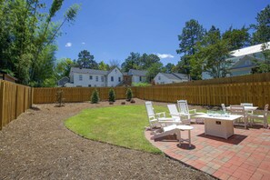 A backyard with a patio area, outdoor furniture, and a wooden fence.