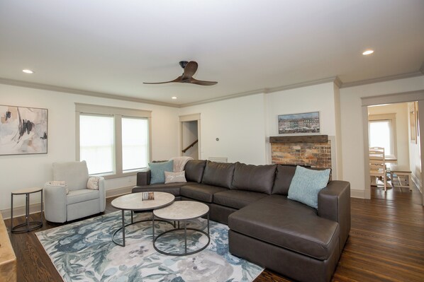 A spacious living room with a sectional sofa, a round coffee table, and a fireplace.