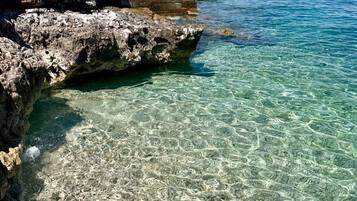 A rocky coastline with clear water, a concrete platform, and a staircase leading up.
