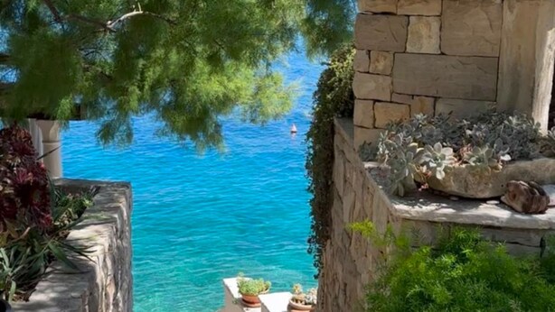 A coastal view with a stone wall, potted plants, and a clear blue sea. - Holiday Home Luna (Korcula)