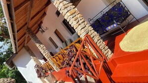 A building with stone pillars, a wooden ceiling, and a balcony with a patterned blue fabric.