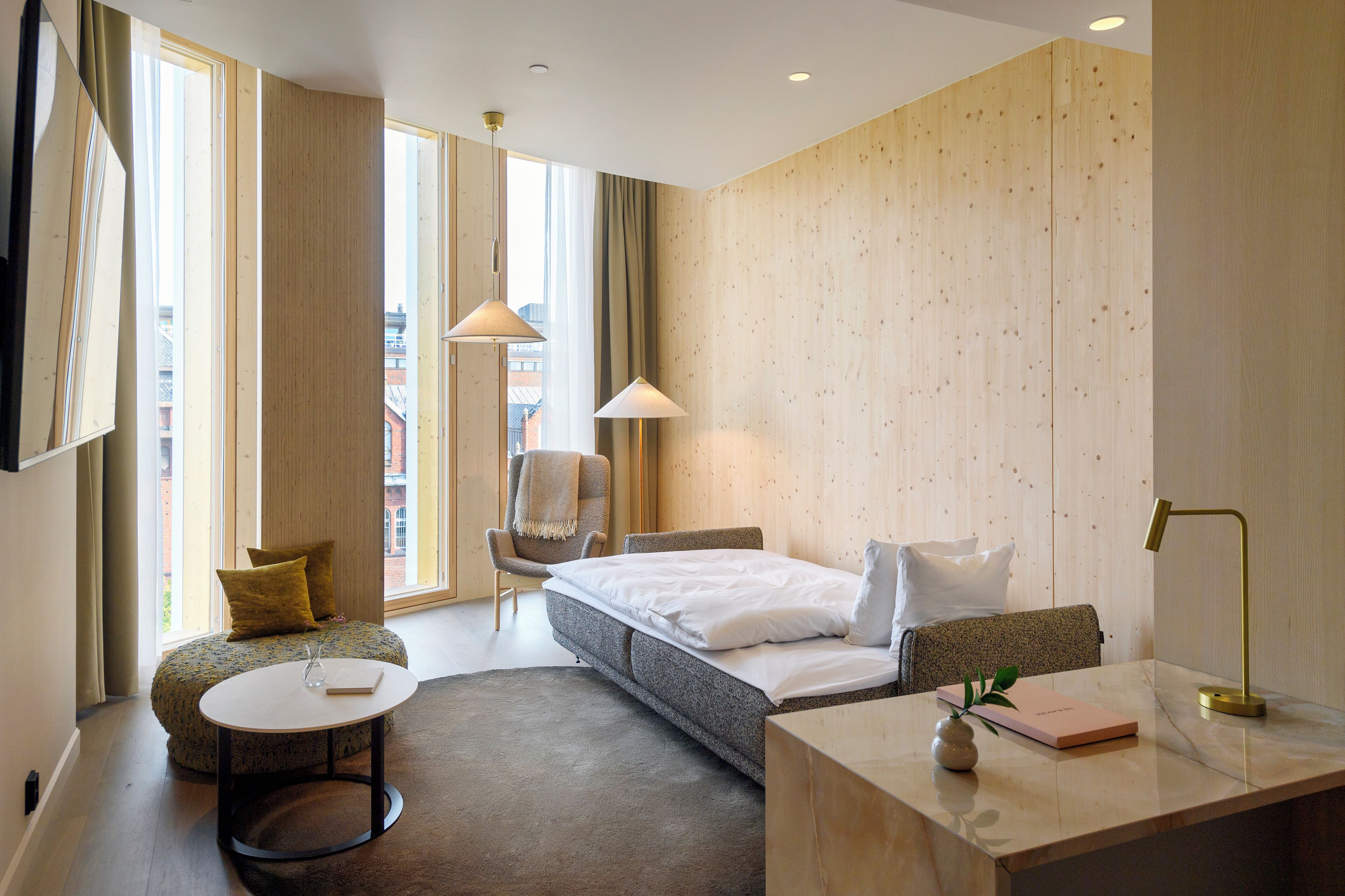Une chambre d’hôtel moderne équipée d’un lit, d’un bureau, d’une chaise et d’une table ronde.