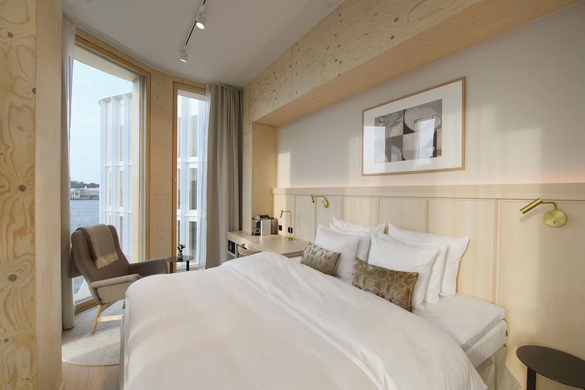 A hotel room with a large bed, a desk, a chair, and a view of the water.