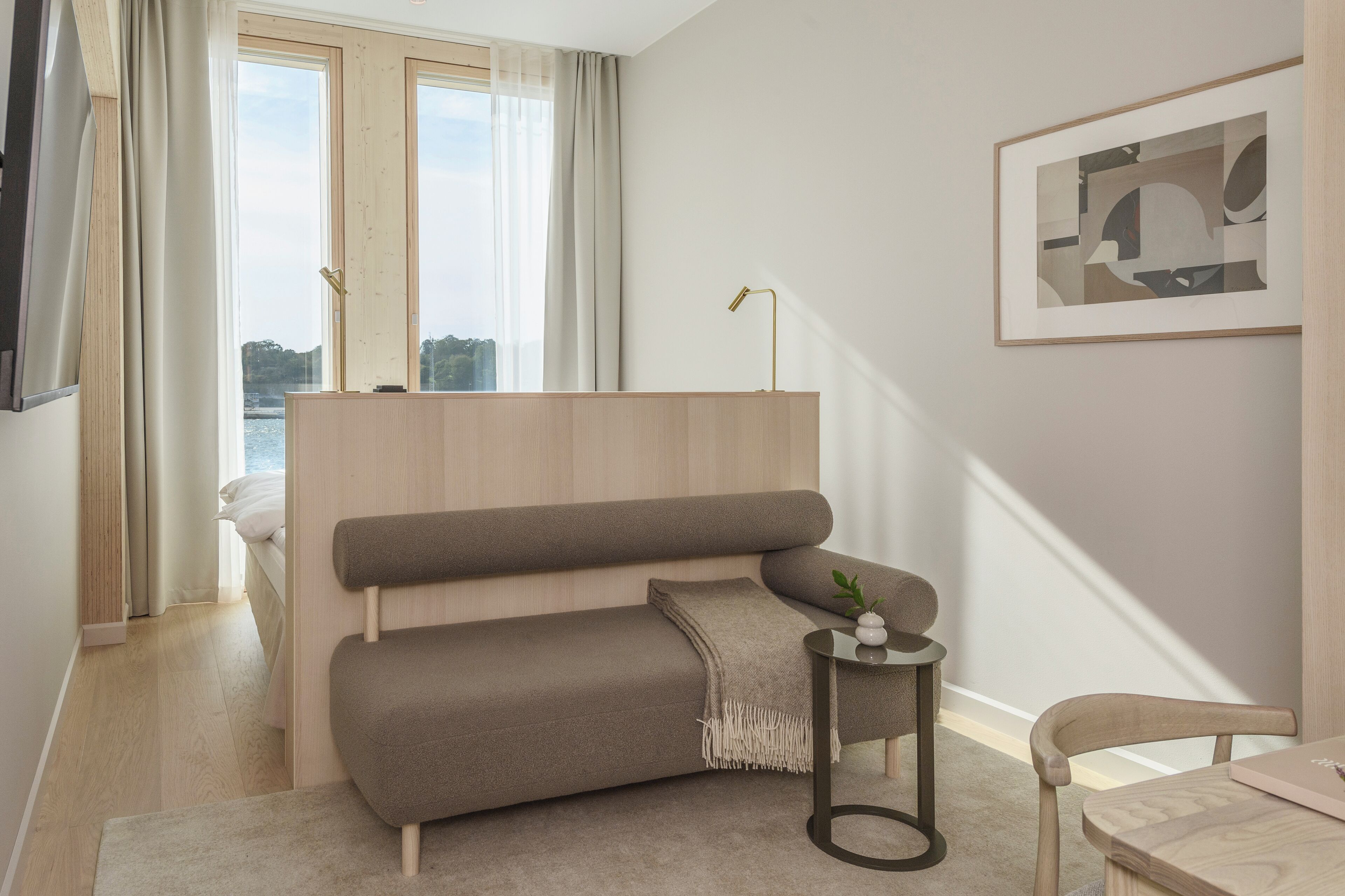 A modern living room with a sofa, a small side table, a chair, and a framed picture on the wall.