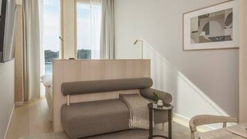 A modern living room with a sofa, a small side table, a chair, and a framed picture on the wall.