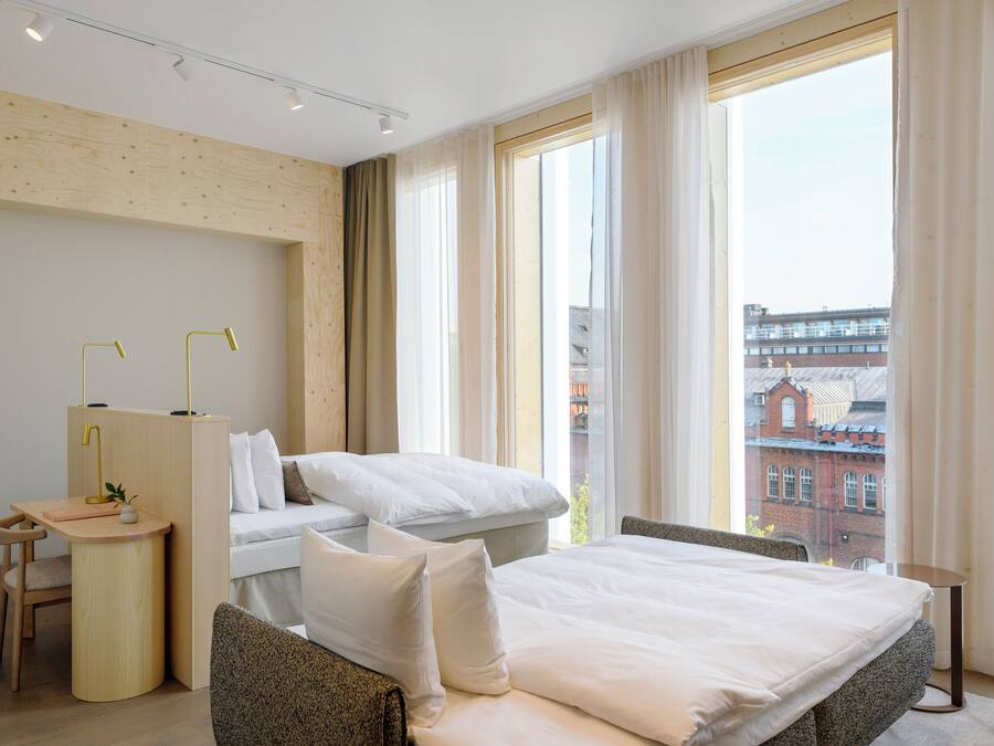 Ein modernes Hotelzimmer mit einem großen Bett, einem Schreibtisch und Blick auf die Stadtlandschaft.