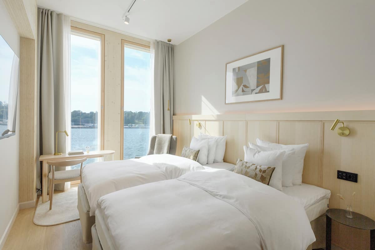 A hotel room with two beds, a desk, and a view of the water.
