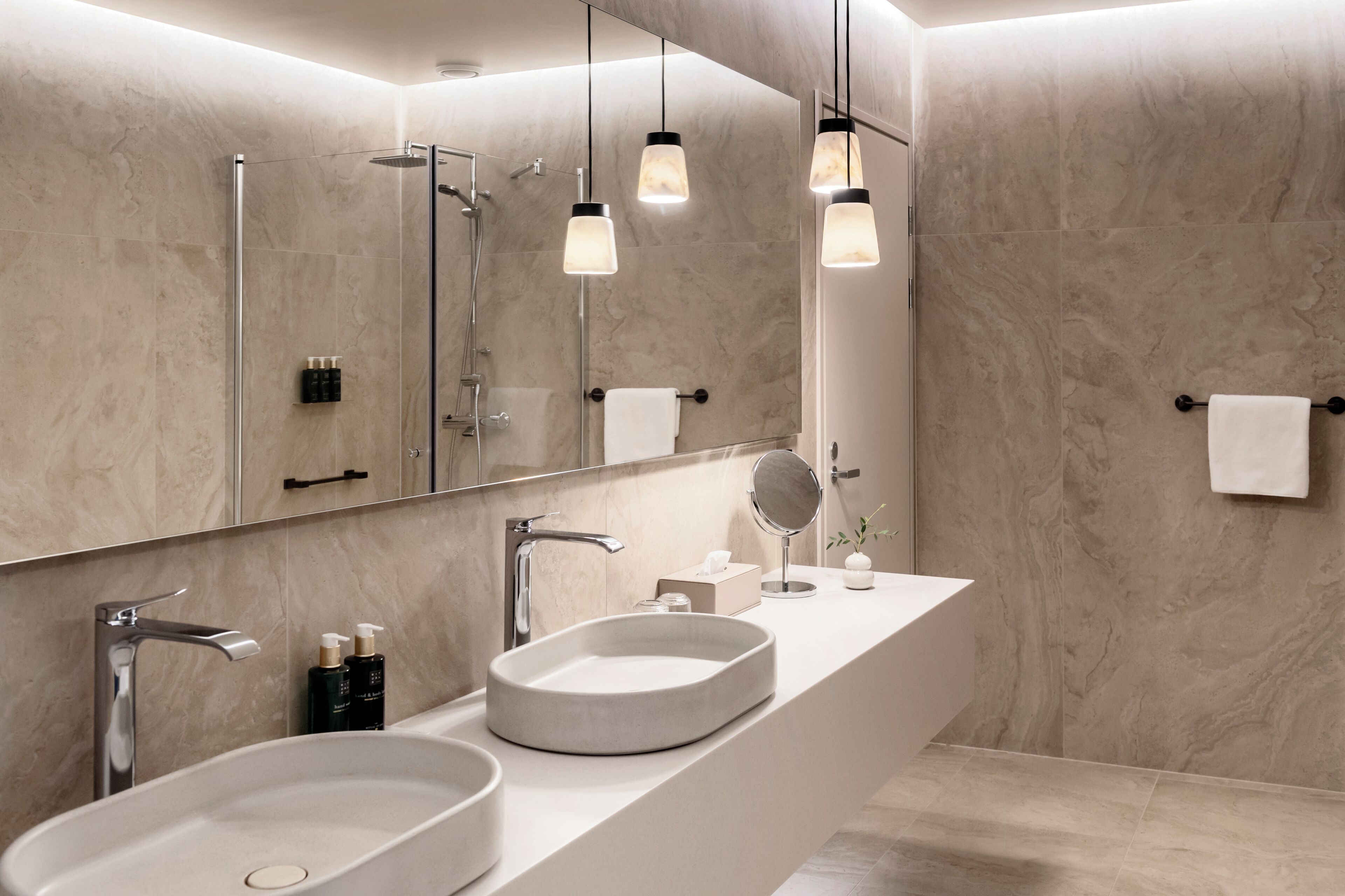 Un baño moderno con un espejo grande, dos lavamanos y una ducha.