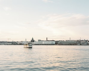 A river with a boat in the foreground and a cityscape in the background. - Solo Sokos Hotel Pier 4 (Helsinki)