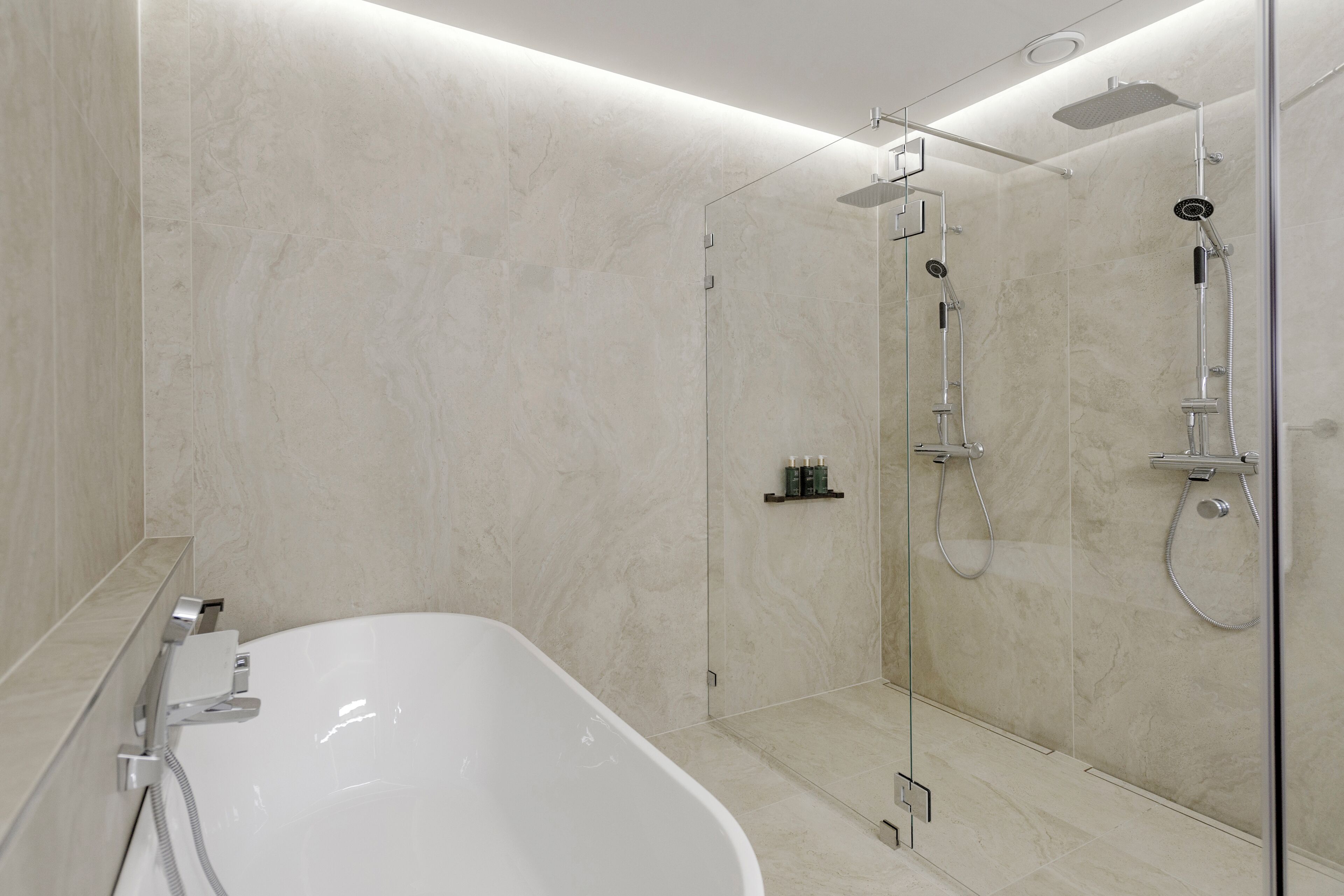 Une salle de bain moderne avec une baignoire sur pieds, une douche à l’italienne et des murs en marbre.