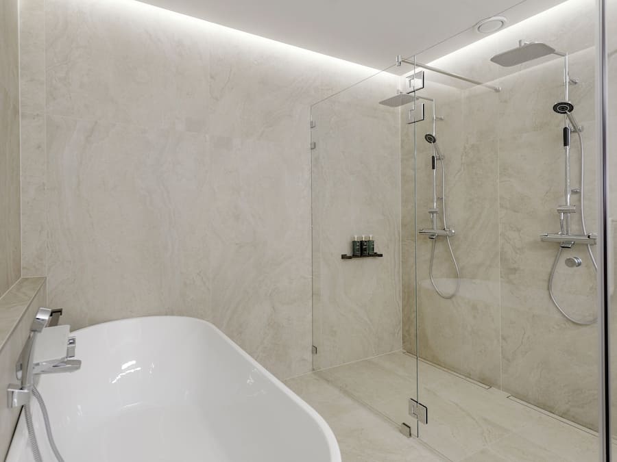 Une salle de bain moderne avec une baignoire sur pieds, une douche à l’italienne et des murs en marbre.