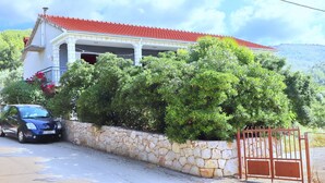 Een huis met een rood dak, een stenen muur en een auto die ervoor geparkeerd staat.