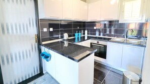 Een moderne keuken met witte kasten, zwarte aanrechtbladen en roestvrijstalen apparatuur.