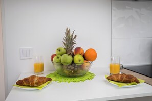 A breakfast setup with a fruit bowl, croissants, and orange juice on a white table. - Apartment Semi (Dubrovnik)
