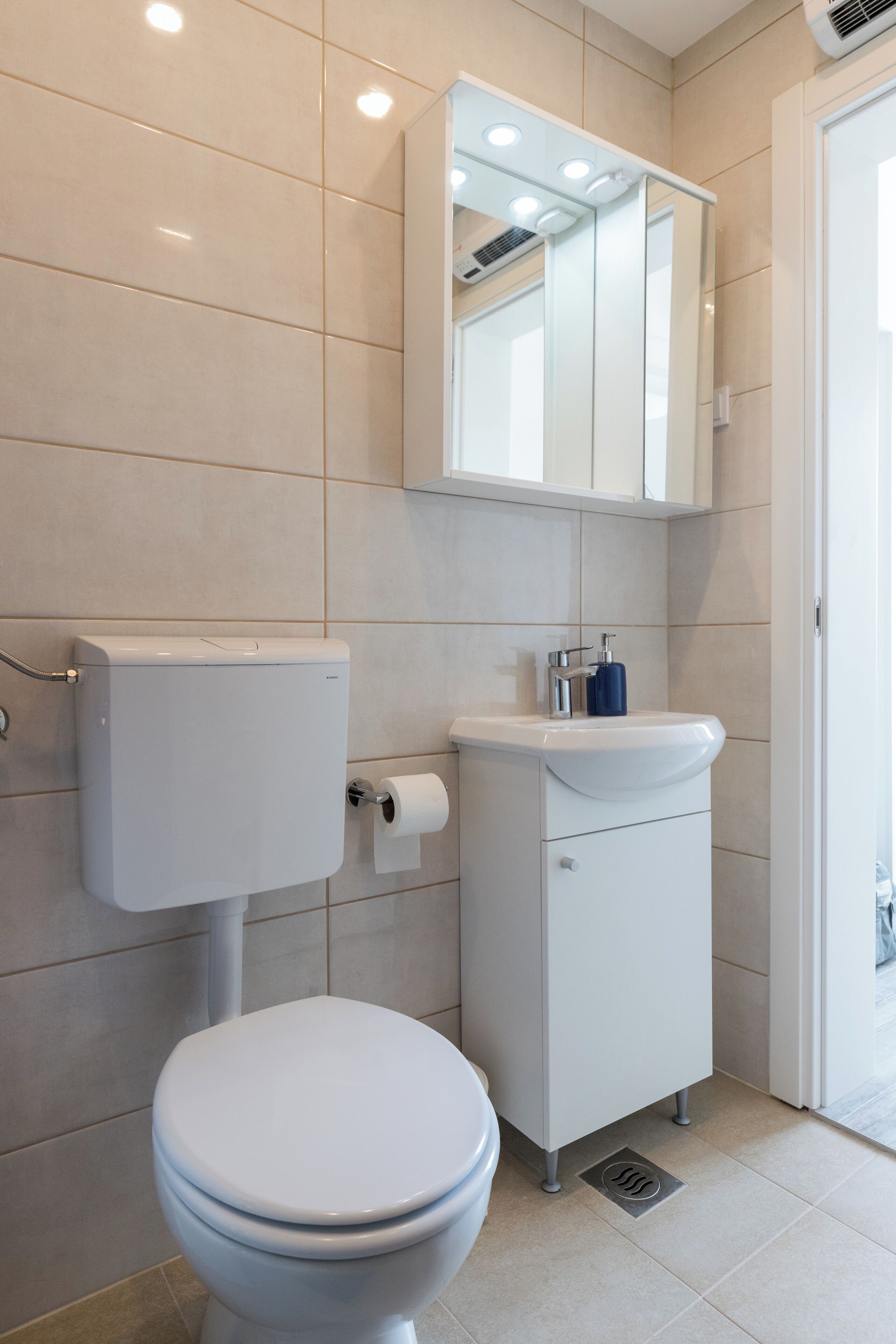 Un baño moderno con inodoro, lavabo y espejo.