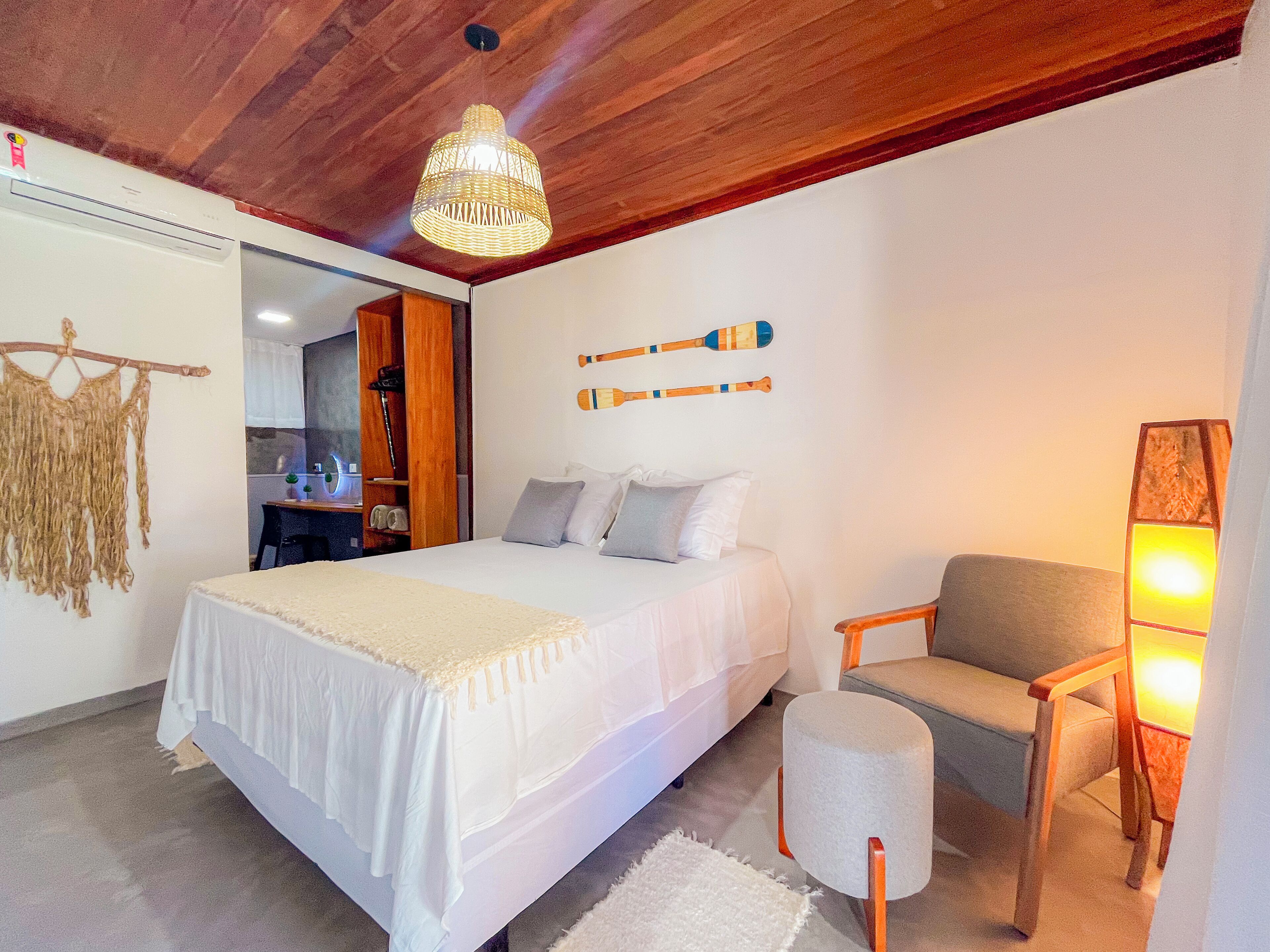Une chambre à coucher avec un grand lit, une chaise, un luminaire suspendu et une étagère fixée au mur.