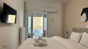 Une chambre d’hôtel avec un lit, un téléviseur fixé au mur, la climatisation et un balcon avec vue.
