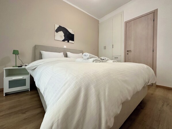 A neatly made bed with white bedding, a green lamp on a bedside table, and a wall-mounted artwork of a horse. - N27 Purple Rainbow (Athens, Greece)