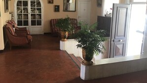 A living room with a fireplace, a large window, and a door. - Hôtel L'ÎLOT FLEURI  (Le Lavandou)