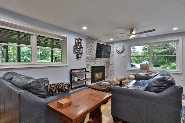 The main living room features a gas fireplace, smart TV, comfy sofas and lounge chairs, and large windows with beautiful views of the Vermont landscape.