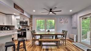 A modern kitchen with white cabinets, a large island, and a dining area with a wooden table and chairs.