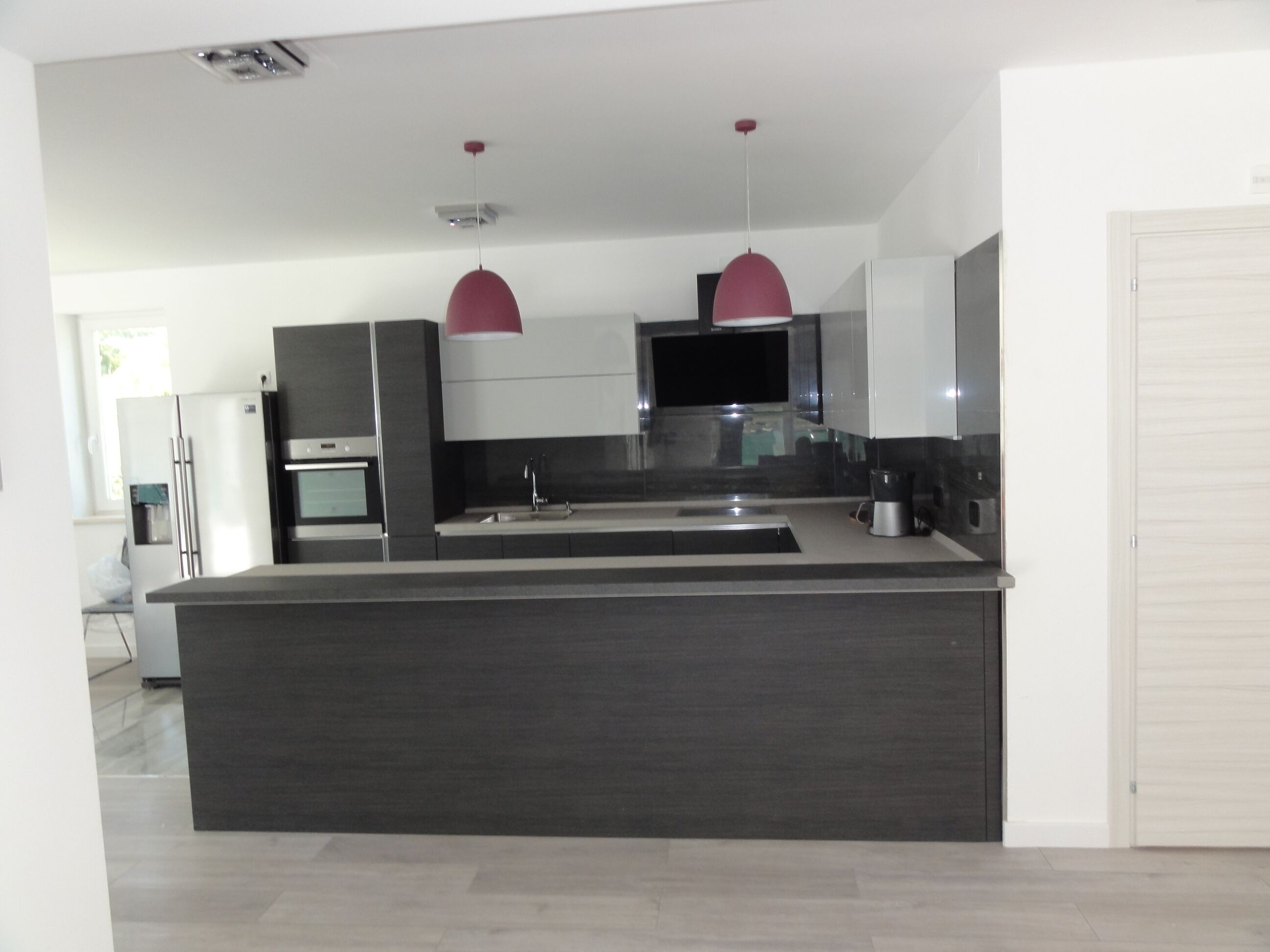 A modern kitchen with a central island, stainless steel appliances, and pendant lighting.