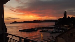 A sunset view from a balcony overlooking a marina with boats, a pier, and distant hills. - Rooms Milena (Dubrovnik)