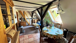 Ein gemütliches Schlafzimmer im Dachgeschoss mit Esstisch, Stühlen und einer kleinen Küchenzeile.