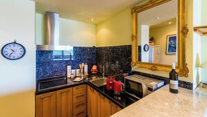 Cocina moderna con extractor de acero inoxidable, una cafetera roja y una botella de vino sobre la encimera.