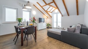 A modern living room with a dining area, wooden beams on the ceiling, and large windows. - Apartments Terra (Dubrovnik)