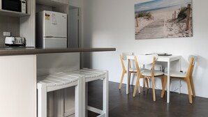 A modern kitchen with a microwave, refrigerator, and a small dining area with a table and chairs. - Headlands 9 - Forster beachfront (Forster)