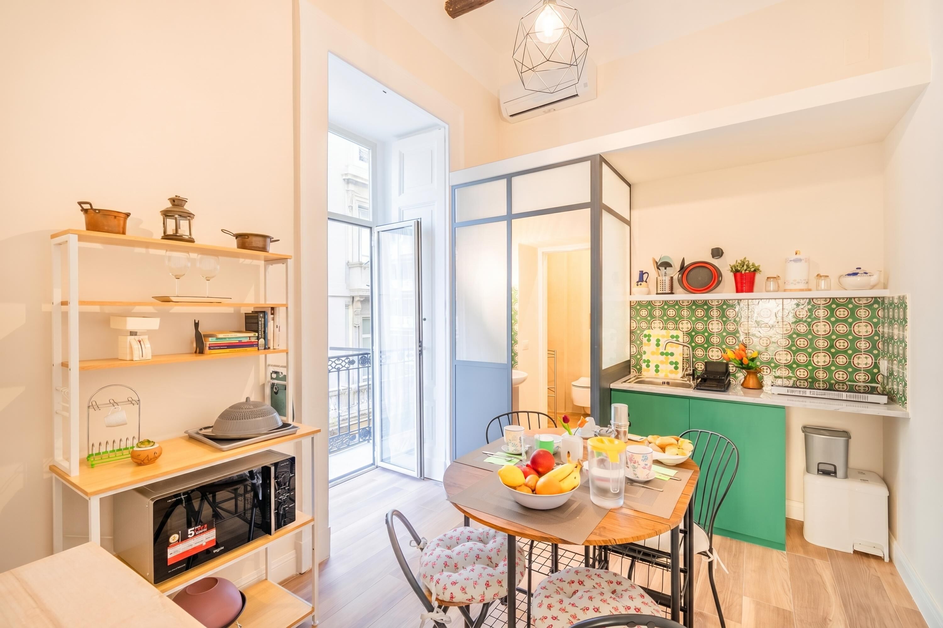A compact living space with a dining area, kitchenette, and a sliding glass door leading to a balcony.