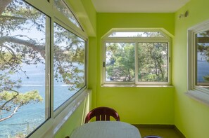 Ein Zimmer mit Blick auf Meer und Bäume, ein Fenster und ein Sessel.