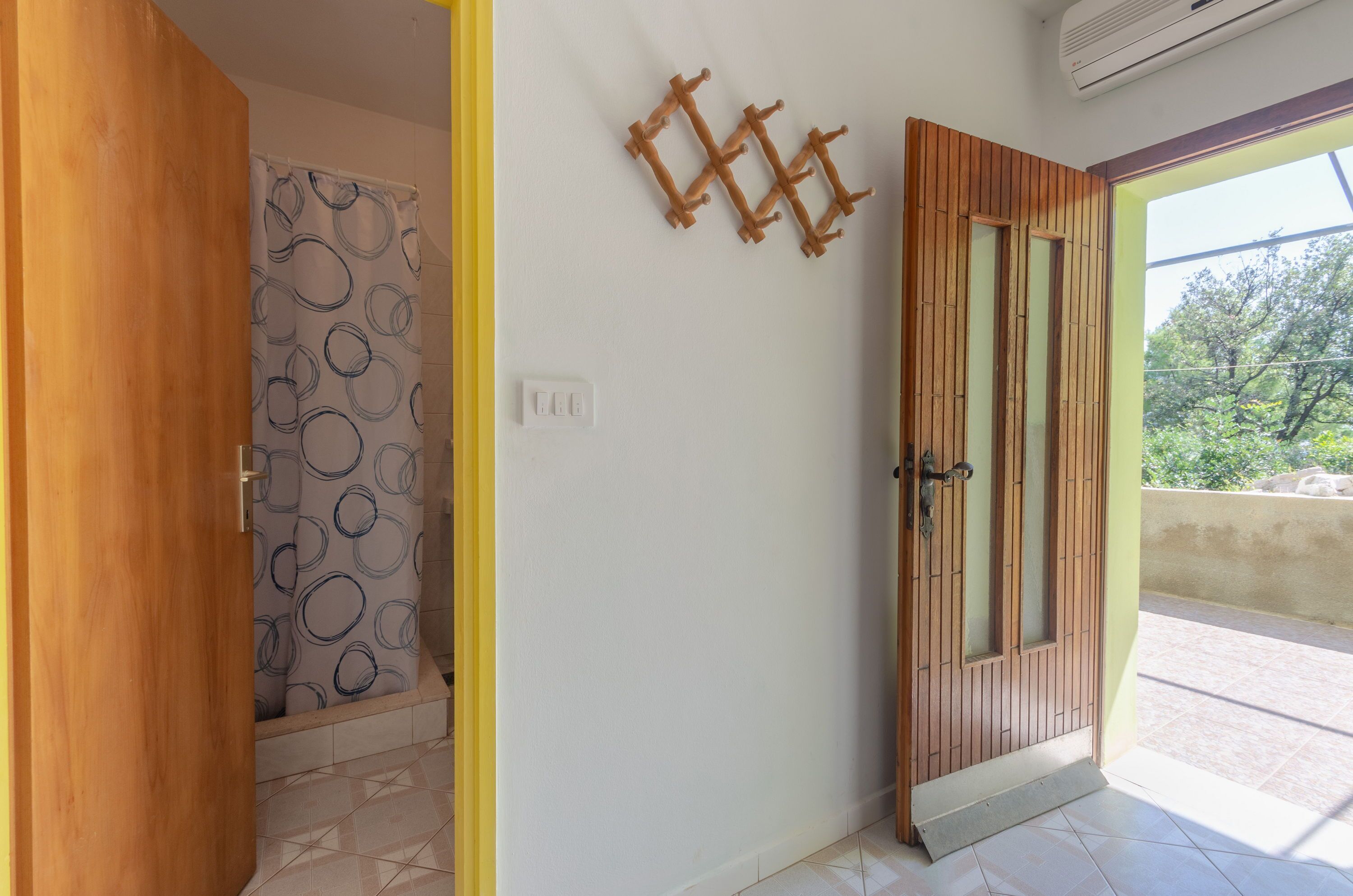 A room with a wooden door, a patterned shower curtain, and a wall-mounted rack.