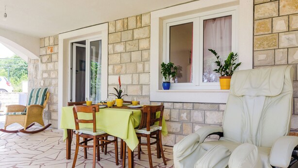 A dining area with a table set for four, surrounded by chairs, a rocking chair, and a massage chair. - Suite Room Little Rea (Zupa dubrovacka)
