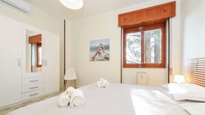 A hotel room with a large bed, a wooden window, a painting on the wall, and a radiator.