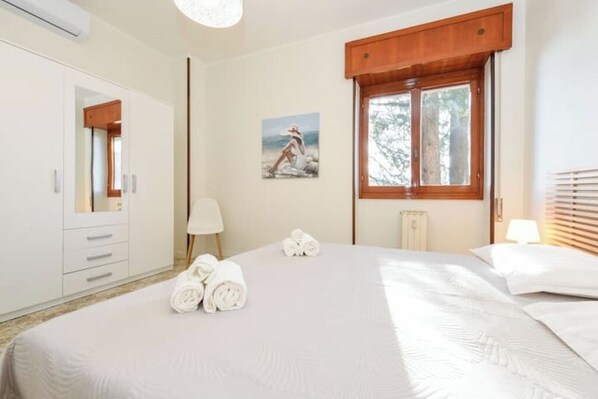 Habitación de hotel con una cama grande, una ventana de madera, un cuadro en la pared y un radiador.