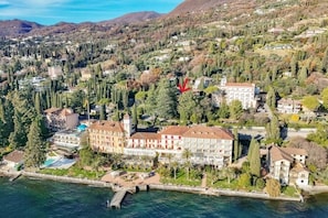 Vista aérea de un pueblo costero con un hotel destacado de varios pisos, una piscina y un muelle que se adentra en el agua.