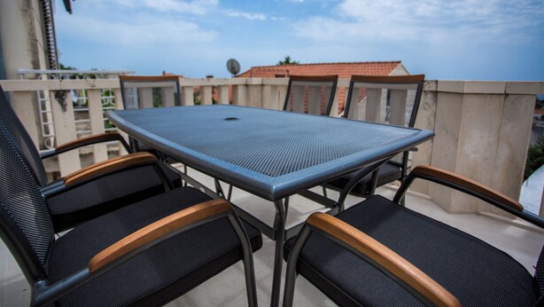 A balcony with a table and chairs, a view of buildings, and a clear sky. - Serious Job Room (Dubrovnik)