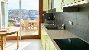 A modern kitchen with green cabinets, a black countertop, and a view of the city through a sliding glass door. - "La Villa du Cap - Sea view - 2/8 travellers (Fécamp)
