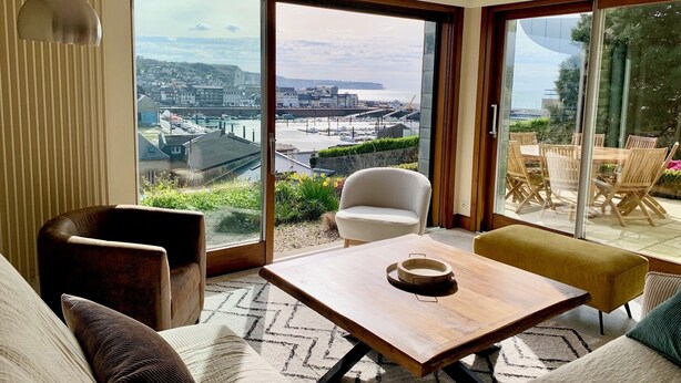 A modern living room with a large sliding glass door leading to a balcony with a view of a coastal town. - "La Villa du Cap - Sea view - 2/8 travellers (Fécamp)
