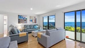 A modern living room with grey sofas, a coffee table, and artwork on the walls. - Sea La Vie - Absolute beachfront!  Amazing sea views! Off peak special! (Port Victoria)
