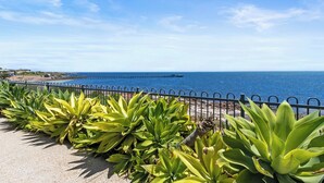 A coastal walkway with a metal railing, lined with green plants, leading to a pier extending into the sea. - Sea La Vie - Absolute beachfront!  Amazing sea views! Off peak special! (Port Victoria)