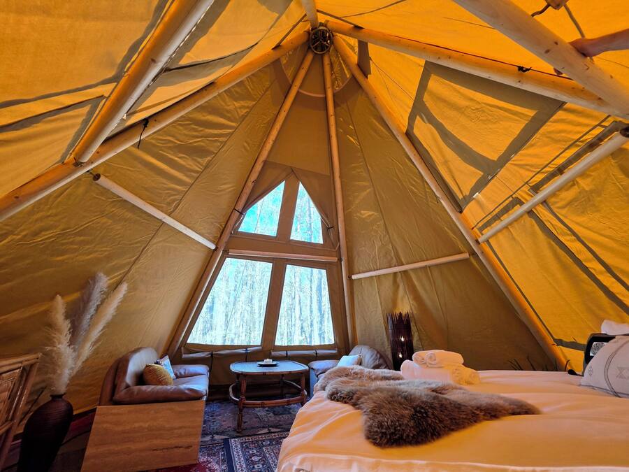 Una carpa con una cama, una mesita y una ventana.