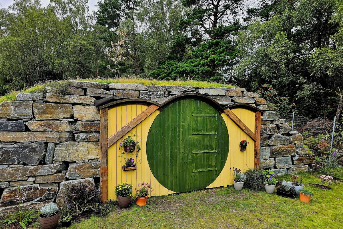 A Hobbit-style door with stone walls and potted plants.