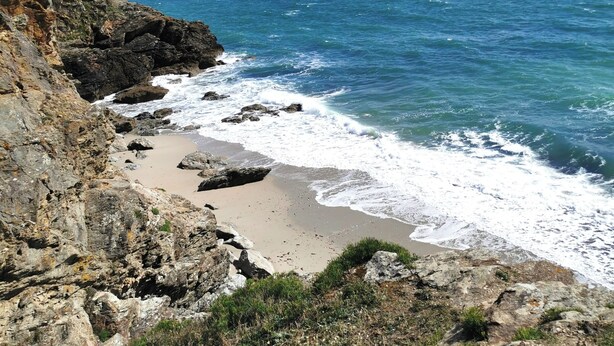 Una costa rocosa con una playa de arena y el océano.